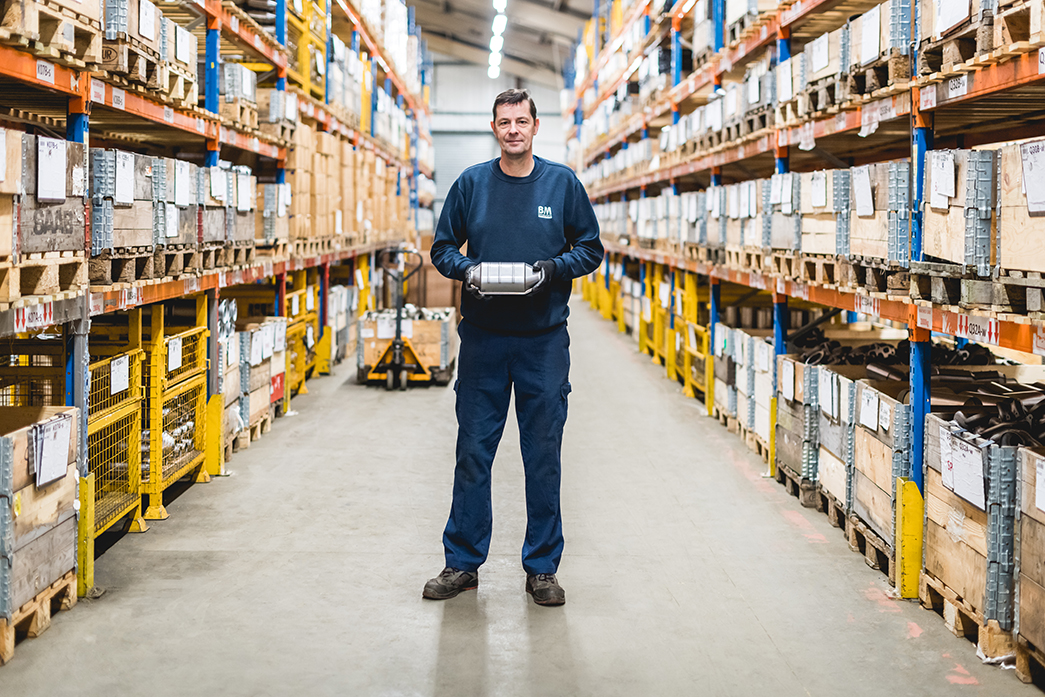 A man in stood next to a pump truck full of car parts in a warehouse for automotive product parts