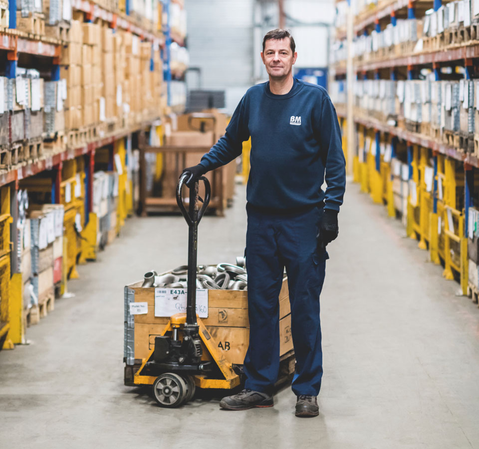 A man in stood next to a pump truck full of car parts in a warehouse for automotive product parts
