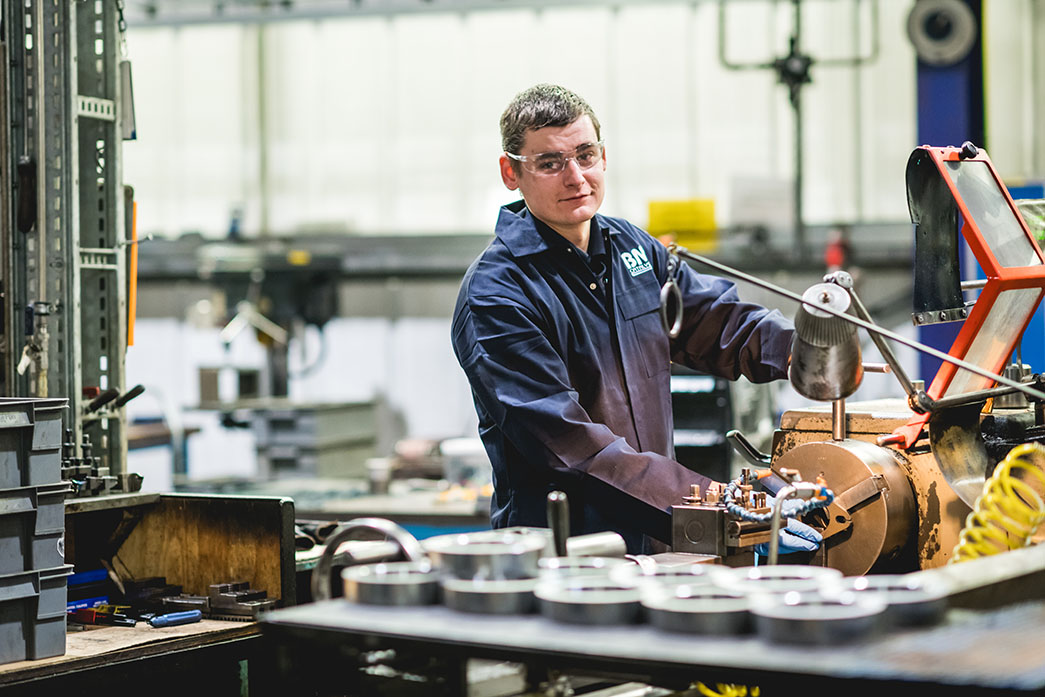 A BM Catalysts worker is wearing overalls and goggles as he works on machinery in the factory
