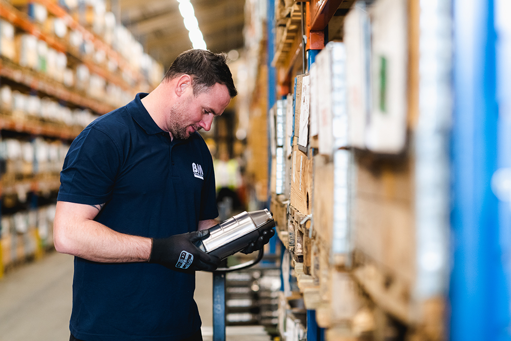 A BM Catalysts worker is looking at parts in their warehouse shelves