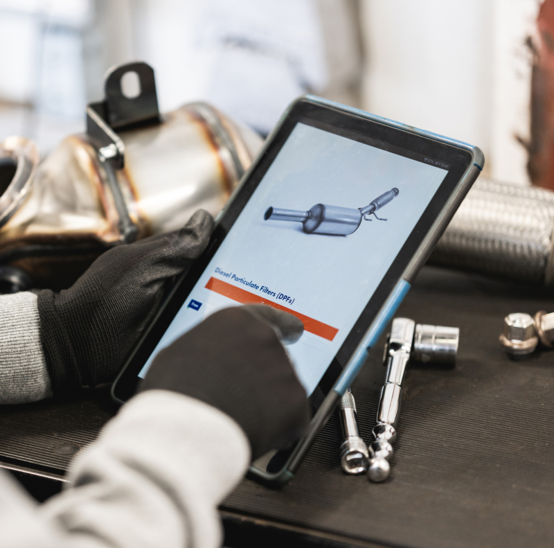 A garage worker is logged into BM Garage Pro on a tablet learning about diesel particulate filters.