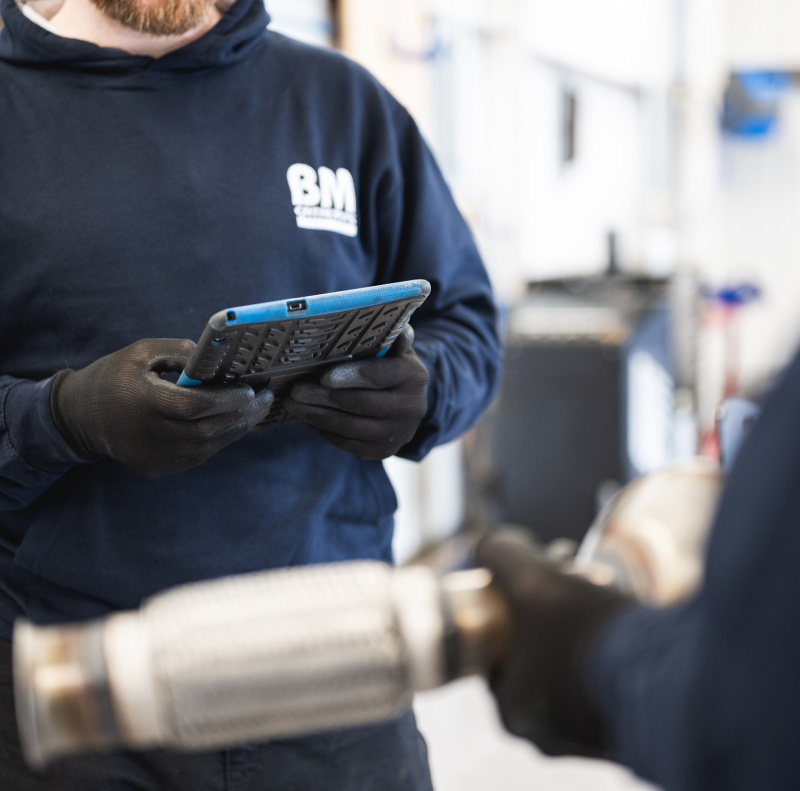 A garage worker is checking a part number on his tablet.