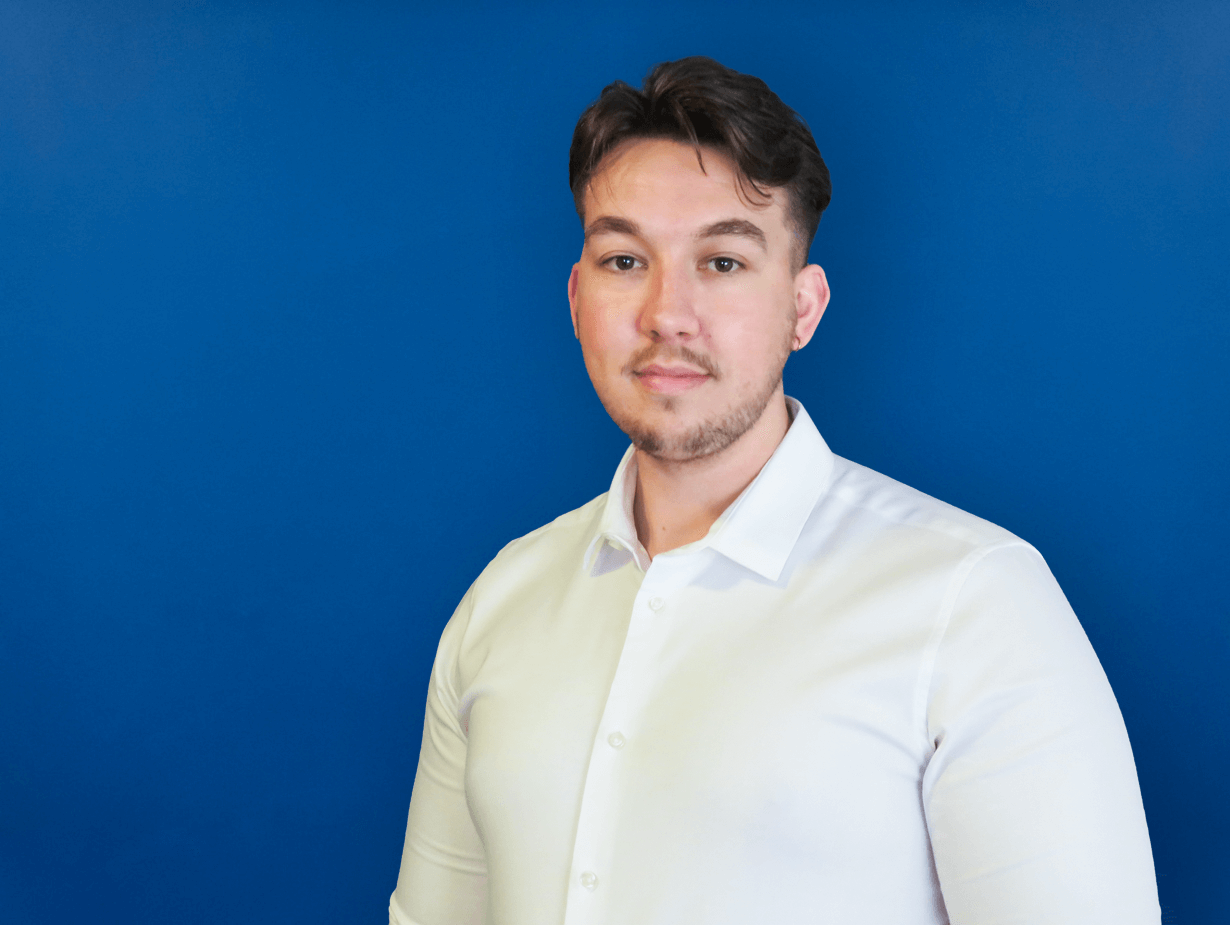 BM Catalysts senior marketing manager Tom Valle stands in front of a plain wall. He is wearing a smart shirt.